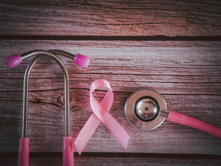 Pink ribbon and stethoscope on wooden table vintage style. Symbol of breast cancer, health care conceptの写真素材