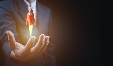 Male hand holding rocket icon that takes off,  rocket is launching and flying out, Business start up, Icon marketing on modern virtual interface.Start up conceptの写真素材