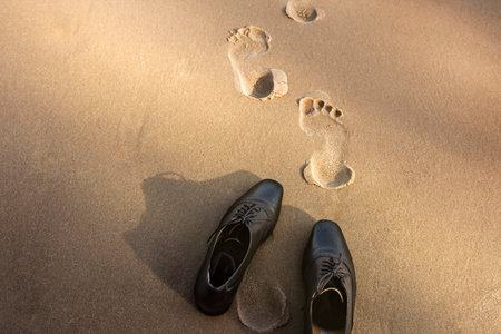 Work Life Balance Concept, Businessman take off his Working Oxford Shoes and leave it on the Sand Beach for Walk into the Sea on Sunny Day. Top Viewの写真素材