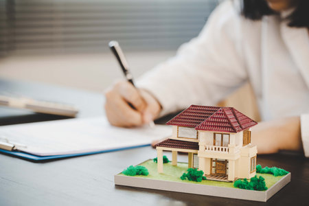 A real estate agent with House model is talking to clients about buying home insurance, Home sales and home insurance concept.の写真素材