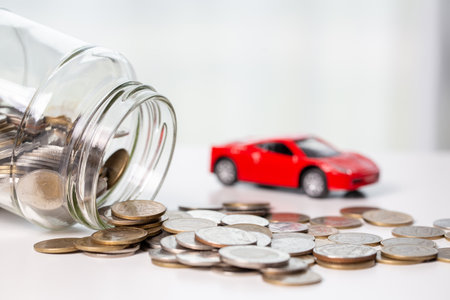 Car toy vehicle with stack coin money on background. Planning to manage transportation finance costs. Concept of car insurance business, saving buy - sale with tax and loan for new car.の写真素材
