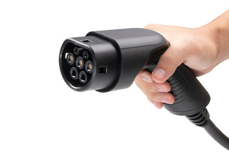 Close up of a man's hand holding a electric car charger isolated on white background with clipping....