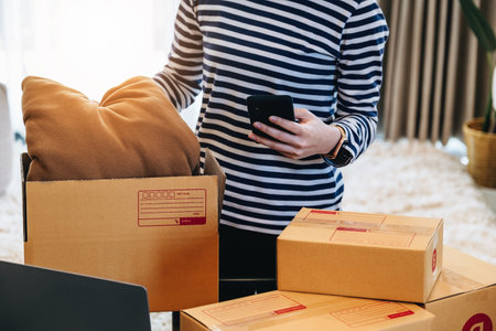Online merchandising business idea, a beautiful girl is packing pillows in a shipping box to prepare...