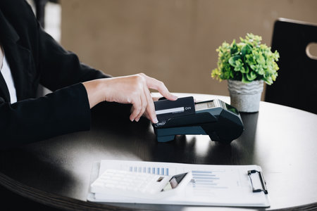 Safe technology concept from using credit card, employee is holding customer's credit card to pay for service or payment via electronic card swipe machineの写真素材