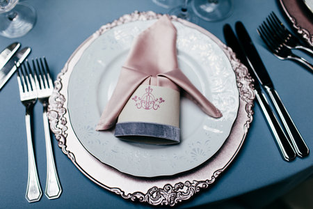 Empty plate with napkin, forks and knives on light blue tableclothes. Beautiful table setting on...