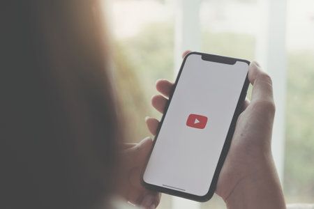 CHIANG MAI ,THAILAND APR 06 2020 : Woman holding a iPhone Xs or iPhone 10 with social Internet service Youtube on the screen Nのeditorial素材