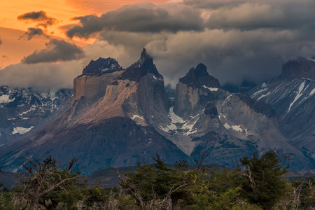 Northward View of Cuernos del Paine (The Horns of Paine) at sundown with beautiful golden light passing through a gap in a dramatic cloudy sky. Torres del Paine National Park, Chilean Patagoniaの写真素材