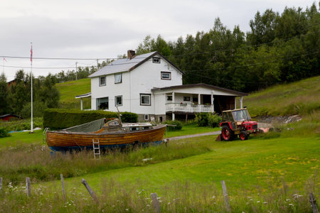 A view on some typical scandinavian home with boat and tractorの写真素材