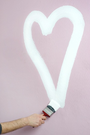 person paints a heart on a pink wallの写真素材