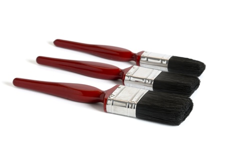 three red paintbrushes of different sizes isolated on a white background