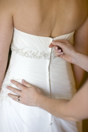 bridesmaid zips up the wedding dress of the brideの写真素材