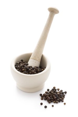 black peppercorns in a white pestle and mortar isolatedの写真素材