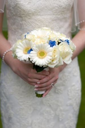 bride holding a wedding bouquet of white roses and gerberaの写真素材