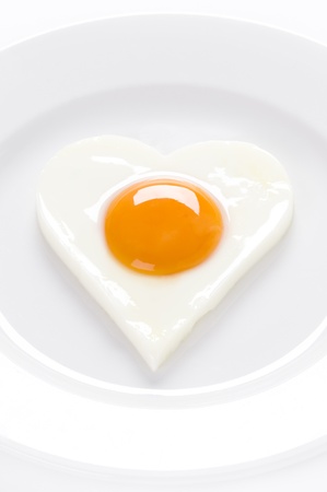 heart shaped cooked egg on a white plateの写真素材