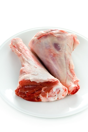 two raw uncooked lamb shanks on a white plateの写真素材