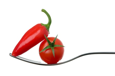 red chili pepper and ripe tomato on a fork against whiteの写真素材