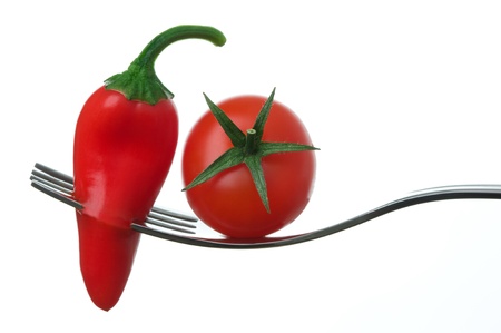 red chili pepper and ripe tomato on a fork against whiteの写真素材