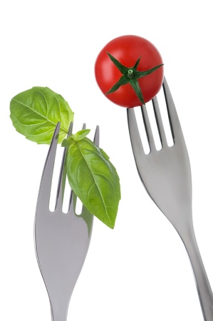 basil and cherry tomato on forks against white backgroundの写真素材