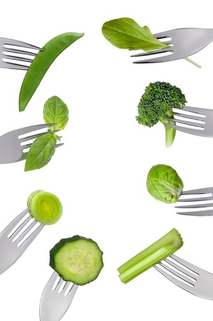 border of fresh green vegetables on forks isolated against white backgroundの写真素材