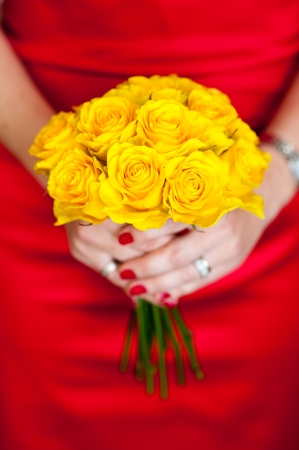 woman in a red dress holding a yellow bouquet of rosesの写真素材