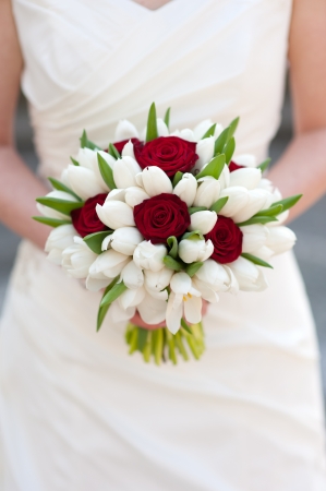 bride holding red rose and white tulip wedding bouquetの写真素材