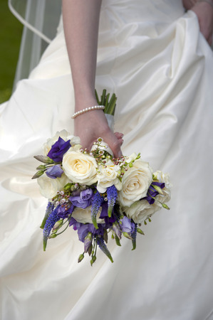 bride holding a purple and white wedding bouquetの写真素材