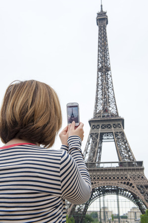 woman taking photographs of eiffel tower paris using a cellphoneの写真素材