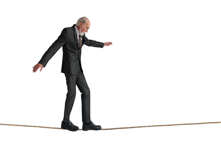 senior man walking a tightrope isolated on whiteの写真素材