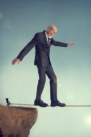 senior man walking on a tightrope or highwireの写真素材