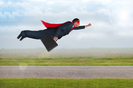 superhero businessman with cape and mask flying の写真素材