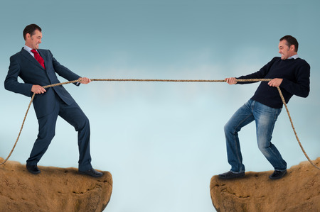 tug of war men pulling rope over a crevasse 