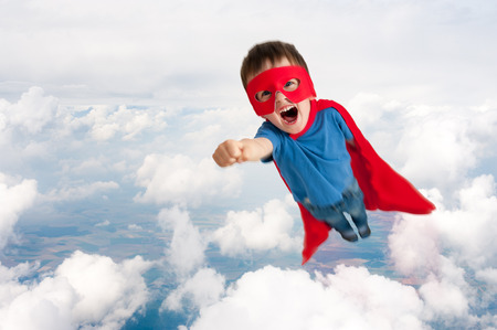 superhero boy child flying upwards through the cloudsの写真素材