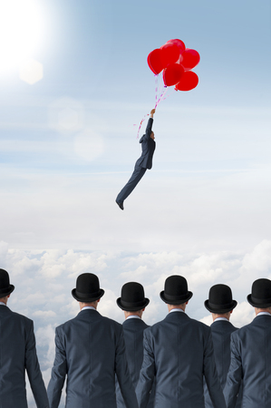 business individuality concept businessman flying away from crowd with balloonsの写真素材