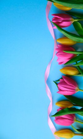 colourfull flowers with pink ribbon on blue background, copyspace, postcard, label concept, vertical shotの写真素材