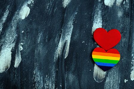 Top view of the heart colored in LGBT pride colors near to the traditional red heart on the abstract...