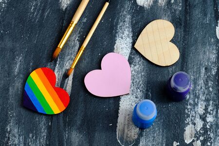Top view of the heart colored in LGBT pride colors near to the traditional pink heart and acrylic paints with brushes on the abstract background. Valentine day conceptの写真素材