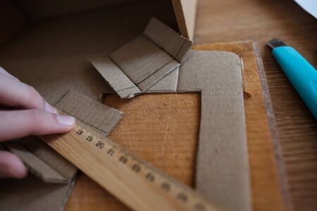 Hand holding ruller, making of diy project out of cardboard waste