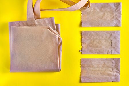 Tote bag made with recycled waste materials and reusable paper packages on the yellow background....