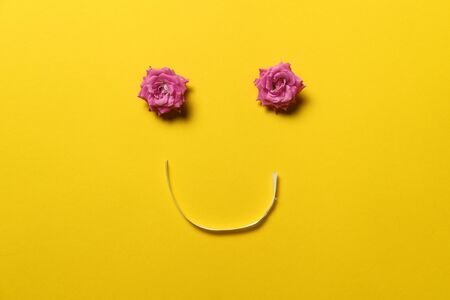 smiley face made out of rose flowers and ribbon, spring blossom concept, happy, yellow backgroundの写真素材