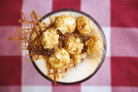 Glass of coffee latte with whipped cream, caramel popcorn, cinnamon