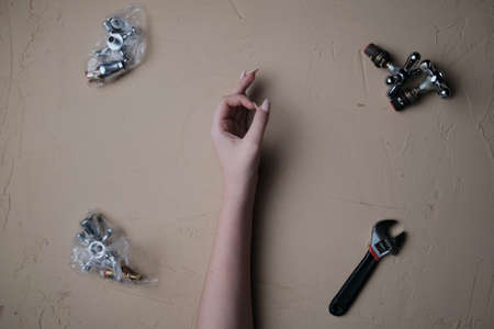Girl hand showing OK sign with a table full of plumbing tools and partsch. Tool for plumbing repair with their hands on tableの写真素材