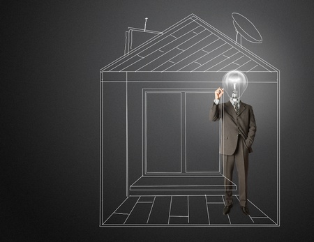 businessman with lamp-head and marker drawing house on glass writeboardの写真素材