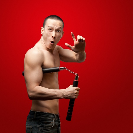 funny muscular shaolin monk with nunchaku in his handsの写真素材