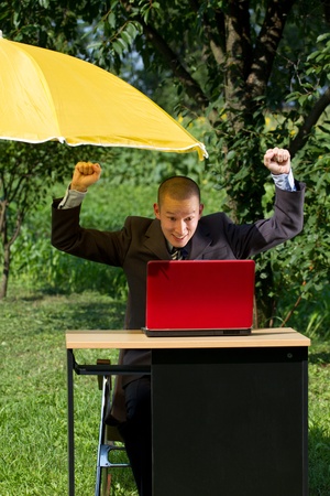 Businessman working outdoors, hiding from the sun under umbrellaのeditorial素材