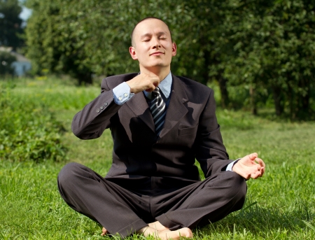 Man businessman meditating outdoors in lotus poseの写真素材
