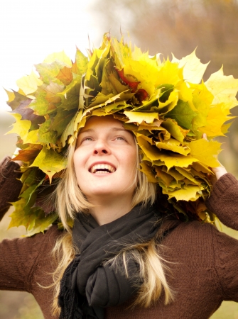 Woman with autumn wreath looking on camera outdoorsの写真素材