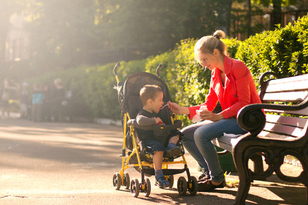 Mother feeding her son in the park outdoorsの写真素材