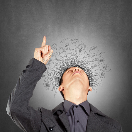 Thinking man with signs and light idea bulb aboveの写真素材