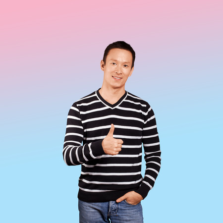 Asian man in striped pullovert, showing well done, isolated on trendy gradient background