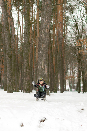 Little boy enjoying sleigh ride. Boy with His Sled While Sledding Down the Hillの写真素材